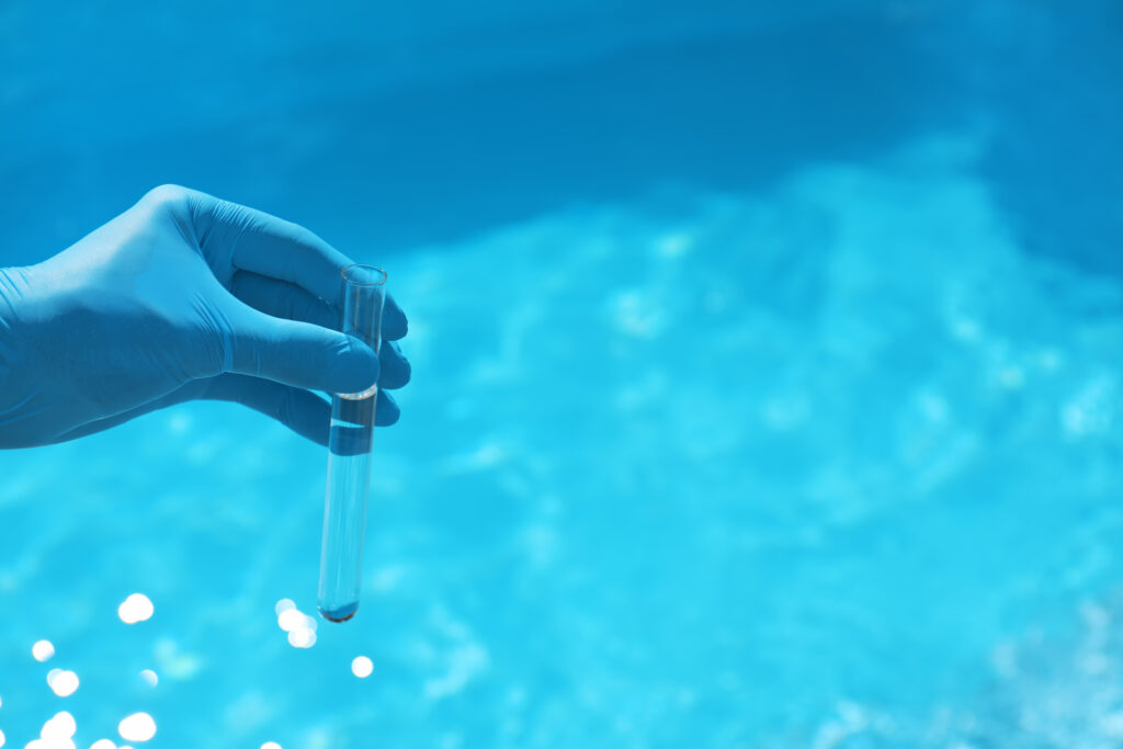 A person measuring pool water chemistry with a test tube